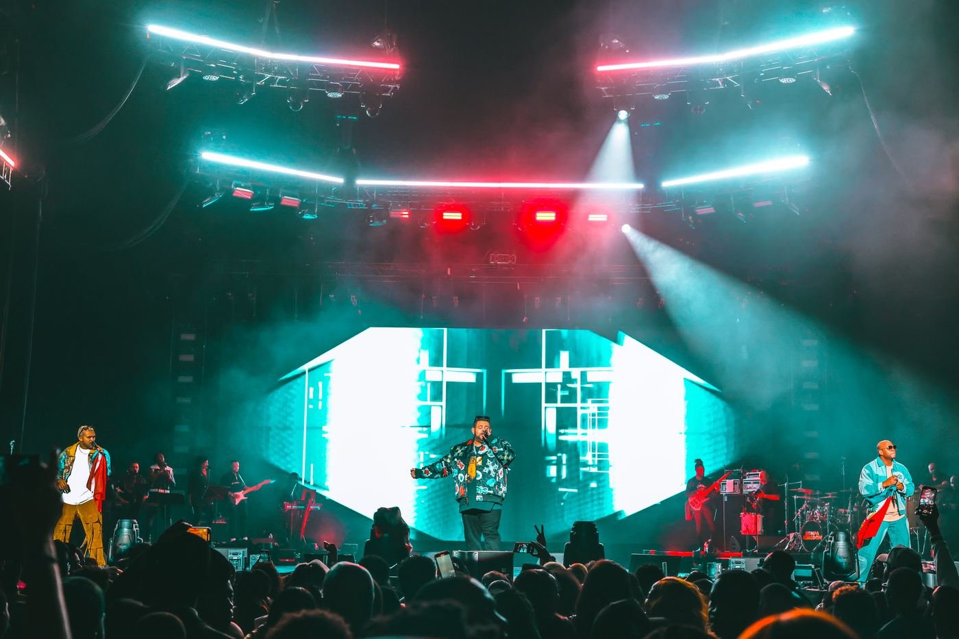Mickael Guirand performing with band members on a colorful lit stage